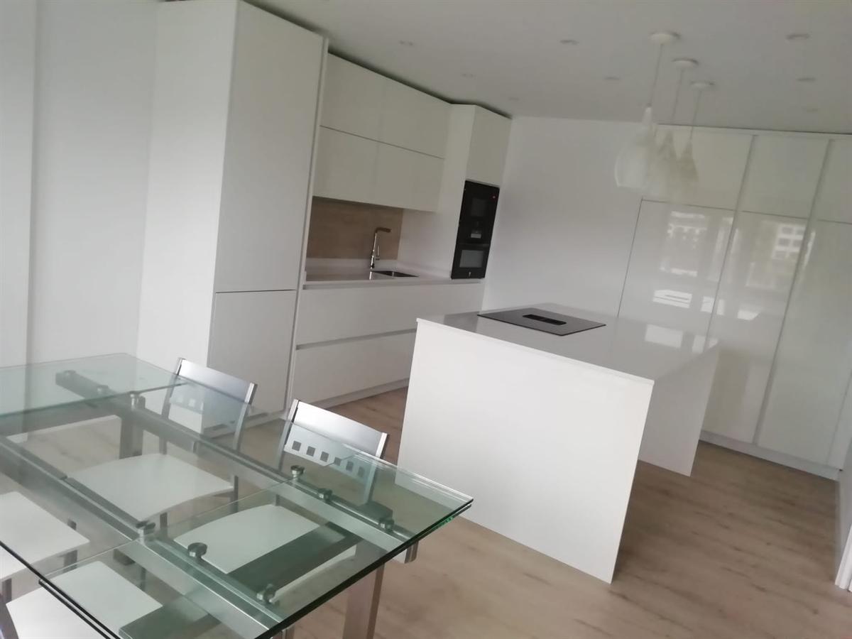 Cocina blanca con isla y mesa de comedor integrada