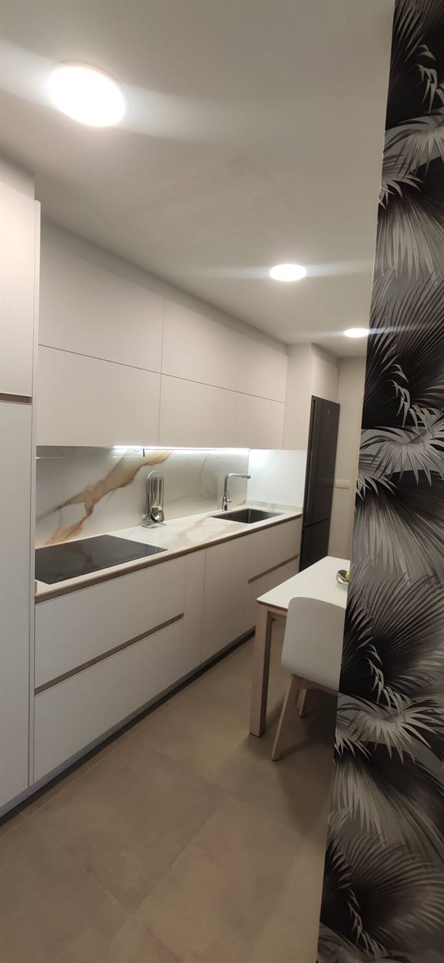 Baño con lavabo redondo sobre encimera blanca y espejo circular