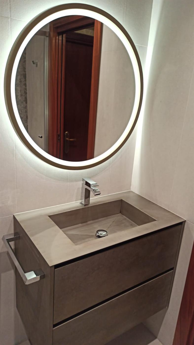 Lavabo sobre encimera blanca con espejo redondo retroiluminado